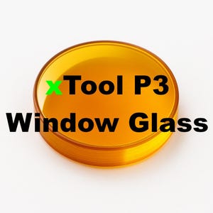 Może przedstawiać: Okrągły, bursztynowy element ochronny ze szkła okiennego do maszyny laserowej xTool P3. Tekst xTool P3 Window Glass jest nadrukowany w kolorze czarnym i zielonym na środku półprzezroczystej, gładkiej i wypolerowanej okrągłej soczewki.