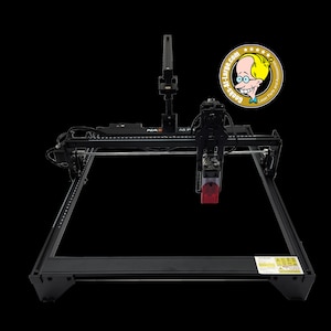 Peut inclure: Machine de gravure laser noire avec une tête laser rouge. La machine a un cadre rectangulaire et un système de portique. L'image comprend un logo qui dit "Geeks-Al-Largo.com Laser Parts and Accessories."