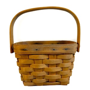 May include: A small, rectangular, woven basket with a brown wooden handle. The basket is made of natural wood and has a woven pattern.