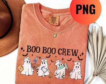 May include: Orange Comfort Colors t-shirt with the text "BOO BOO CREW" and a graphic of ghost nurses. The design includes bats, a spider web, and a pumpkin. A gold necklace is visible.