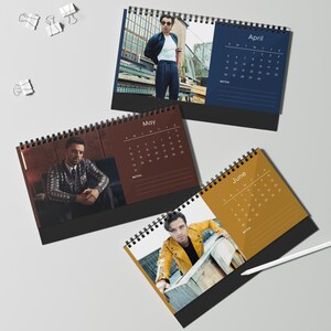 May include: Three spiral-bound desk calendars featuring images of men and monthly calendar grids. The calendars are open to April, May, and June. The April calendar has a navy blue background, May is brown, and June is gold.
