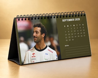 May include: A spiral-bound desk calendar for September 2025 featuring a photograph of a man in a white racing shirt with logos including Orlen, Honda, Visa, and Hugo. The right side displays the month, dates, and a section for notes.