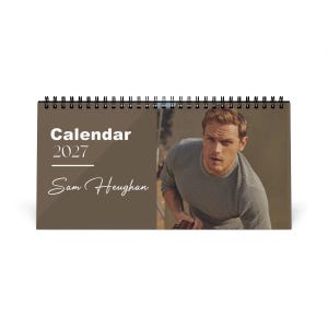 Puede incluir: Un calendario de escritorio con encuadernación en espiral para el año 2027 con una cubierta marrón y el texto blanco Calendar 2027 y Sam Heughan. El lado derecho muestra una fotografía de una persona de cabello castaño claro con un suéter gris.