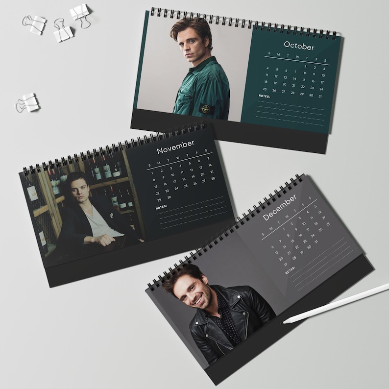 May include: Three spiral-bound desk calendars with images of a man. The calendars are open to the months of October, November, and December. Each calendar has a black base and a dark gray background with white text.