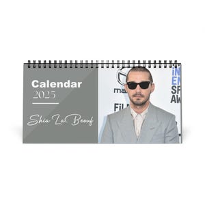 May include: A spiral-bound desk calendar for 2025 featuring a photo of Shia LaBeouf. The calendar has a gray background with the text "Calendar 2025" and "Shia LaBeouf" in white. The calendar is on a white background.