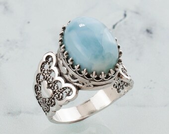 May include: A silver ring featuring a blue oval gemstone set in a filigree design.