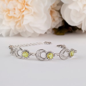 May include: A silver bracelet with a delicate filigree design and three yellow gemstones.
