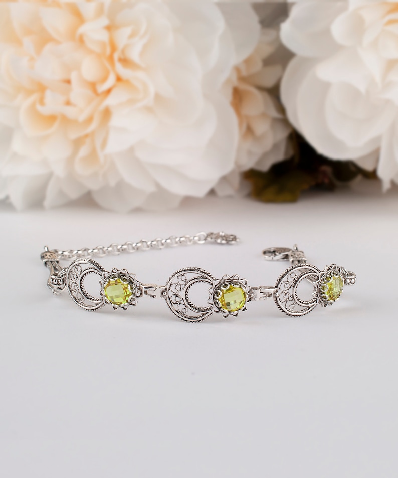 May include: A silver bracelet with a delicate filigree design and three yellow gemstones.