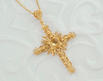 May include: A gold filigree cross pendant with a small clear gemstone in the center. The cross is detailed with intricate floral designs.