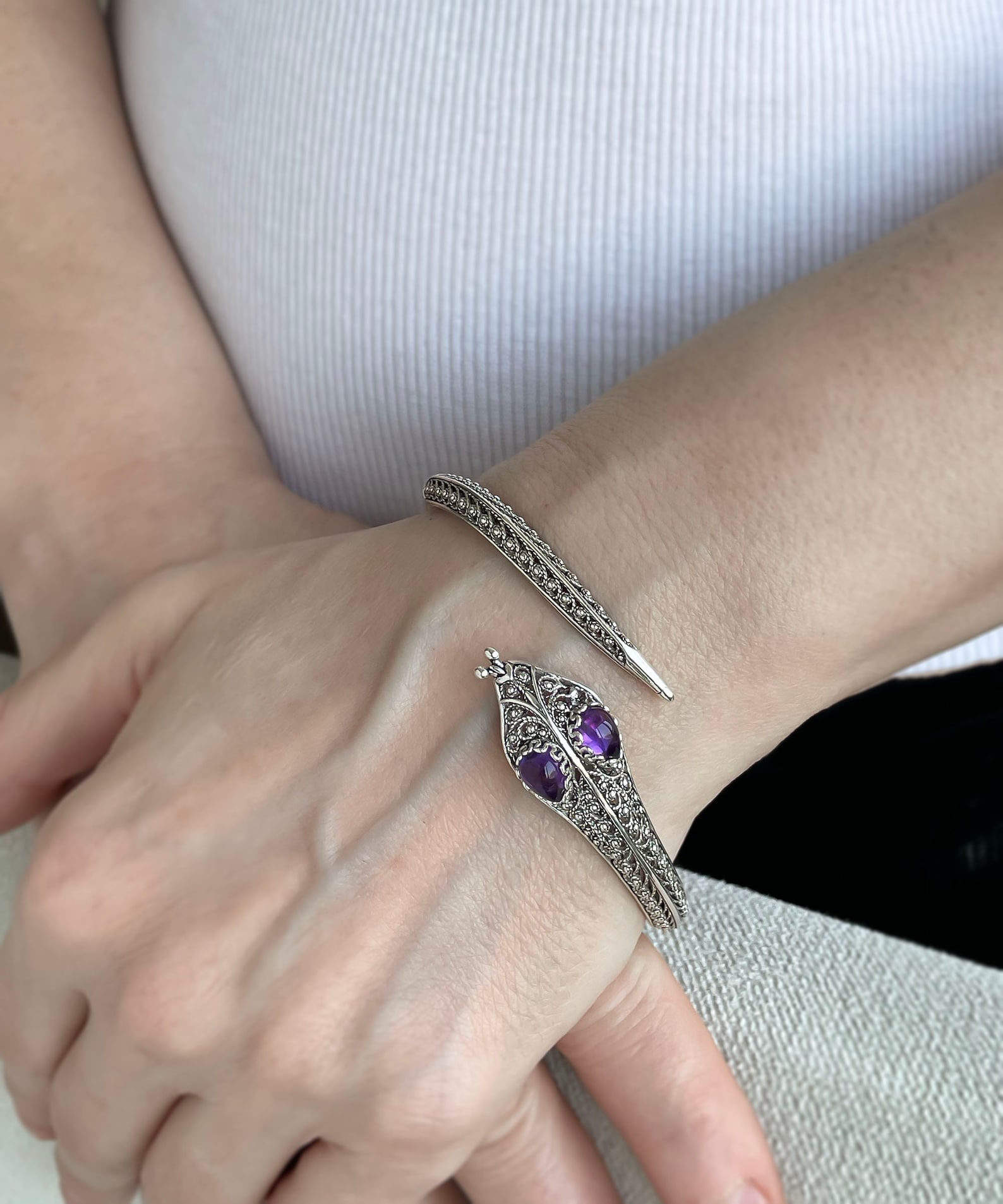 Amethyst-eyed serpent cuff bracelet worn on wrist, handcrafted in sterling silver filigree