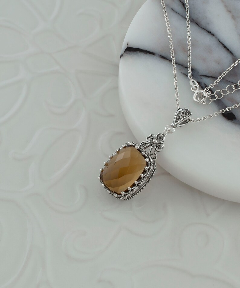 May include: A silver necklace with a brown gemstone pendant. The pendant is set in a filigree design and has a faceted gemstone.