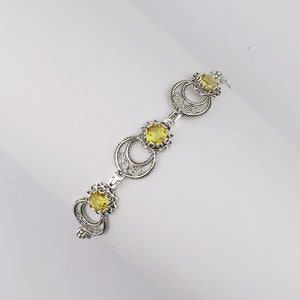 May include: A silver bracelet with three yellow gemstones set in intricate filigree designs.