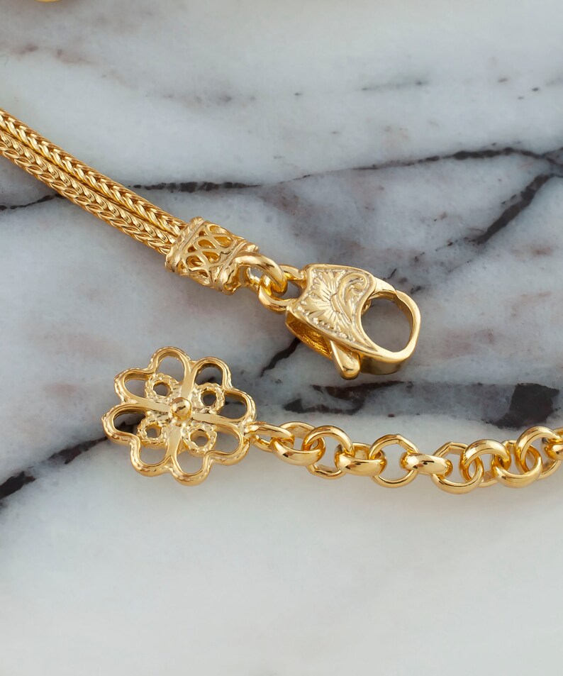K&ouml;nnte beinhalten: Goldkette Armband mit einem zarten Blumenanh&auml;nger und einem Karabinerverschluss.