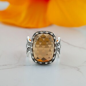 May include: A silver ring with a large, faceted, light brown gemstone set in a detailed, ornate design.