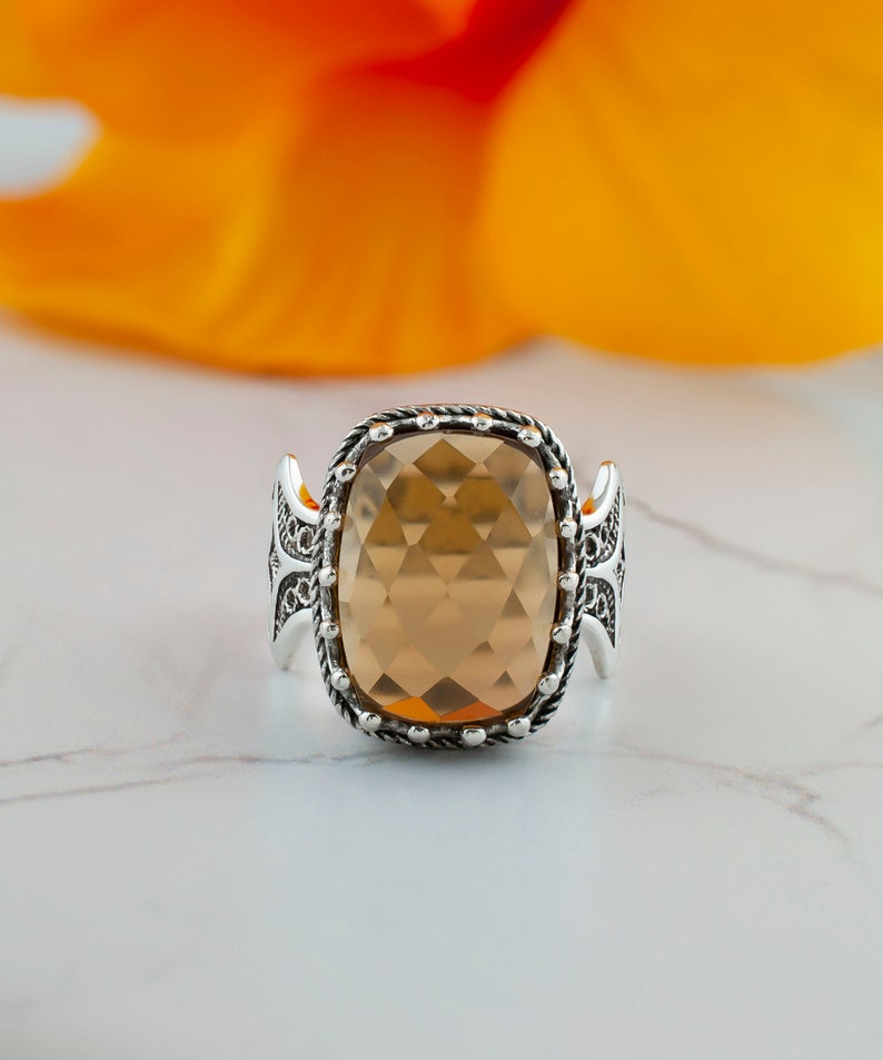 May include: A silver ring with a large, faceted, light brown gemstone set in a detailed, ornate design.