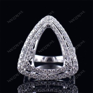 Pode incluir: Um anel de prata com um design triangular. O anel é adornado com pequenos diamantes ao redor das bordas e no centro.