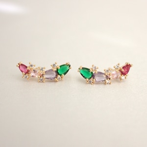 Pode incluir: Um par de brincos de ouro com um grupo de pedras preciosas verdes, rosa e roxas. Os brincos são engastados em um delicado design floral.