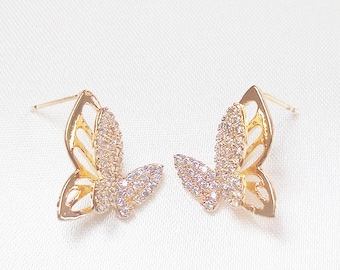 Puede incluir: Un par de pendientes de mariposa de oro con detalles de cristal transparente. Los pendientes son pequeños y delicados, y serían un gran regalo para una ocasión especial.