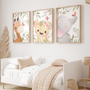 Peut inclure: Trois impressions encadrées avec des illustrations à l'aquarelle d'une girafe, d'un léopard et d'un éléphant. Chaque animal porte une couronne de fleurs et est entouré de feuilles vertes. Les impressions sont étiquetées "Girafe", "Léopard" et "Éléphant".