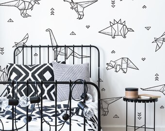 May include: A black metal bed frame with a geometric patterned duvet and pillows. The white wall features black origami dinosaur shapes and triangles. A small black side table holds a book and a decorative box.
