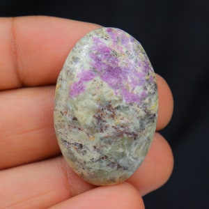 Peut inclure: Pierre précieuse en cabochon de forme ovale avec une base vert clair, gris et marron avec un motif en étoile rose et violet.