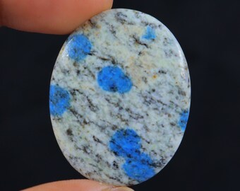May include: Oval shaped cabochon of blue and white kyanite gemstone. The stone has a white base with blue spots.