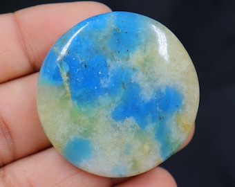 May include: A round, polished cabochon of blue and white chrysoprase. The stone has a swirling pattern of blue and white, with a hint of green.
