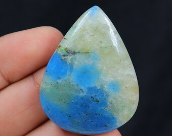 May include: A teardrop-shaped cabochon gemstone with a mix of blue, green, and white colors. The stone has a mottled appearance with swirls of color.