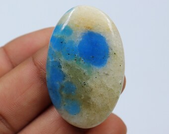 May include: Oval shaped cabochon gemstone with a white base and blue and green inclusions.