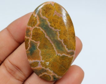 May include: A smooth, oval-shaped, polished stone with a brown, green, and white pattern. The stone has a natural, organic look.