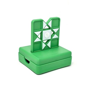 May include: A green plastic game with a white star-shaped target and a white button in the center. The game is on a green base.