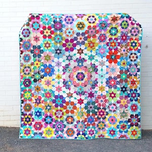 May include: A colorful quilt with a geometric pattern of hexagons and stars. The quilt is made of various fabrics in shades of pink, blue, green, yellow, and red.