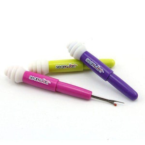 May include: Three seam rippers in pink, green, and purple, each with a white, swirled top and the text "seam-fix". The tools have a metal blade for removing stitches.