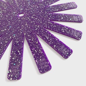 May include: A set of purple quilting tools with a speckled, glittery design. The tools are arranged in a circular pattern, radiating outwards from a central point. The text "Quilt with Kate" is visible on each tool.