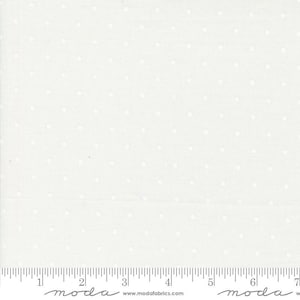 May include: White fabric with small white dots. The fabric is measured with a ruler in inches. The ruler has the word "moda" printed on it.