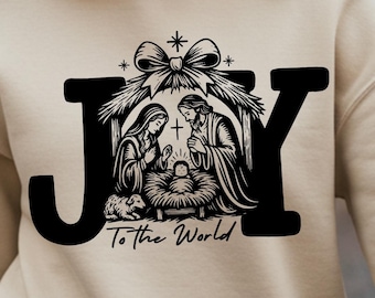 May include: A beige sweatshirt with a black graphic that reads "JOY To the World." The graphic depicts a nativity scene with Mary, Joseph, and baby Jesus. The sweatshirt has long sleeves and a crew neck.