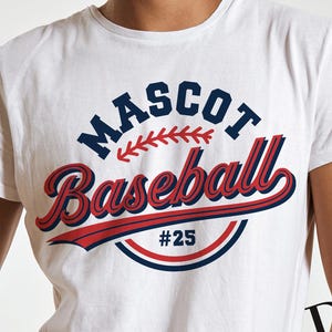 Peut inclure: T-shirt blanc avec un motif sur le thème du baseball. Le motif comprend le mot "MASCOT" en bleu marine, "Baseball" en script rouge avec un contour bleu marine et le numéro "25". Un graphisme de baseball rouge et marine complète le design.