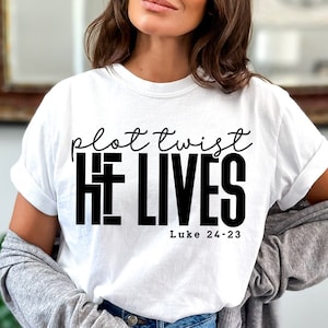 May include: White t-shirt with black text that reads "plot twist HE LIVES Luke 24-23".