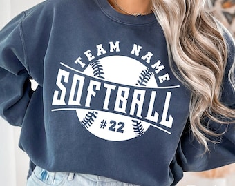 May include: A dark blue sweatshirt with a white graphic of a softball and the text "TEAM NAME SOFTBALL #22".