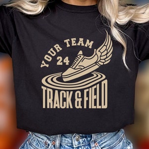 May include: A black t-shirt with a gold graphic of a running shoe with wings and the text "Your Team 24 Track & Field".