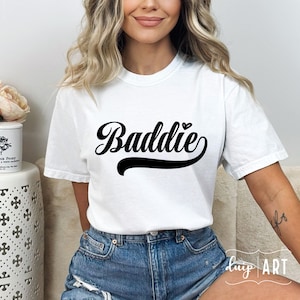 K&ouml;nnte beinhalten: Wei&szlig;es T-Shirt mit dem Text "Baddie" in schwarzer Schrift mit einem kleinen Herzen &uuml;ber dem "e".