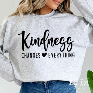 May include: Grey sweatshirt with the text "Kindness Changes ♥ Everything" in black.