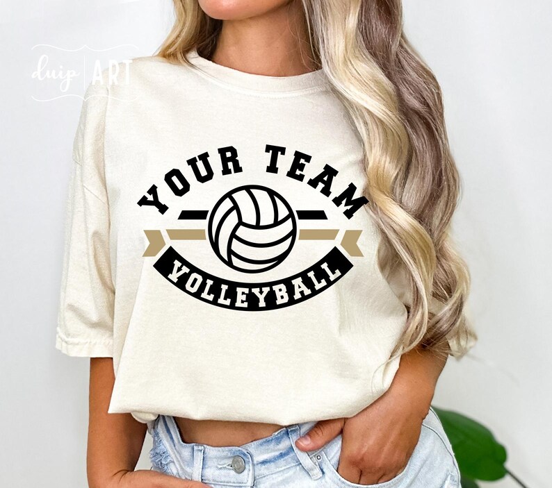 May include: A white t-shirt with a black and gold graphic design featuring a volleyball and the text "Your Team Volleyball".