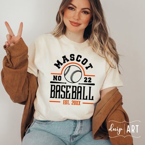 May include: White t-shirt with a black and orange baseball graphic. The graphic says "Mascot No 22 Baseball Est. 20XX".