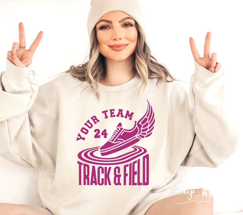 May include: A white sweatshirt with a pink graphic of a running shoe with wings and the text "YOUR TEAM 24 TRACK & FIELD"