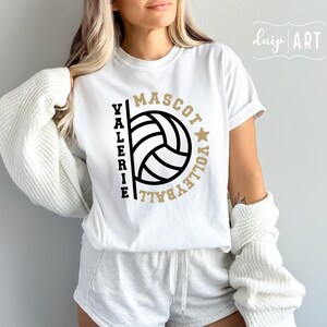 May include: White t-shirt with a volleyball graphic and the text "Valerie Mascot Volleyball" in black and gold lettering.
