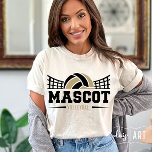 May include: A white t-shirt with a black and gold volleyball graphic and the text "MASCOT VOLLEYBALL".