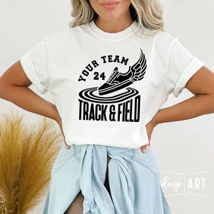 May include: White t-shirt with black text and graphic. The text reads "Your Team 24 Track & Field" and the graphic is a black sneaker with wings.