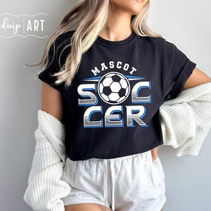 Pu&ograve; includere: Maglietta nera con un design grafico bianco che dice "MASCOT SOCCER" con un pallone da calcio al centro. La grafica &egrave; in un design a strisce blu e bianche.