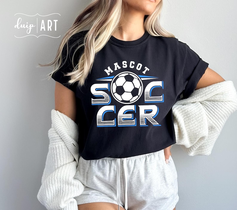 Pu&ograve; includere: Maglietta nera con un design grafico bianco che dice "MASCOT SOCCER" con un pallone da calcio al centro. La grafica &egrave; in un design a strisce blu e bianche.